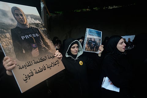 Women hold posters showing Al-Mayadeen TV reporter Fatima Ftouni, left, and, in another poster, Hezbollah's Al-Manar TV correspondent Ali Shoeib, center, and cameraman Ali Ftouni during their funeral at a temporary cemetery in Dahiyeh, Beirut's southern suburbs, Beirut, Lebanon, Sunday, March 29, 2026.