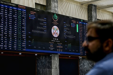 A stock broker looks at share prices on a digital board during a trading session at the Pakistan Stock Exchange (PSX) in Karachi on April 1, 2026.