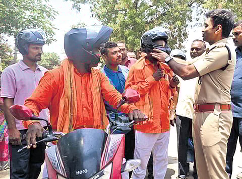 SP P Shabarish puts on helmets on commuters on the NH-365 in Mahbubabad district