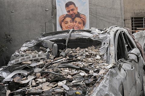 A poster of a man and two kids who were killed in an Israeli airstrike that was hit their house, is seen through a destroyed car in Saksakiyeh village, south Lebanon, Friday, April 3, 2026.