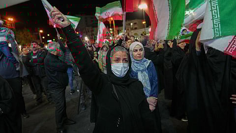 Women hold Iranian flags during a pro-government gathering in a square in Tehran, Iran, Sunday, April 5, 2026. 