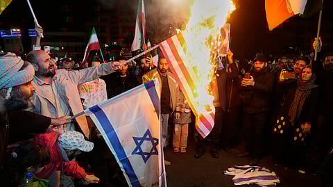 Iranian pro-government demonstrators burn the U.S. and Israeli flags during a gathering after announcement of a two-week ceasefire in the war with the United States and Israel, at the Enqelab-e-Eslami, or Islamic Revolution, Square, in Tehran, Iran, Wednesday, April 8, 2026. 