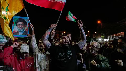 Demonstrators chant slogans as they hold Iranian flags and a poster of the Supreme Leader Ayatollah Mojtaba Khamenei in a gathering after the announcement of a two-week ceasefire in the war with the US and Israel at the Enqelab-e-Eslami, or Islamic Revolution, Square, in Tehran, Iran, Wednesday, April 8, 2026.