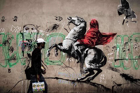 A man walks past a recent artwork by street artist Banksy in Paris 