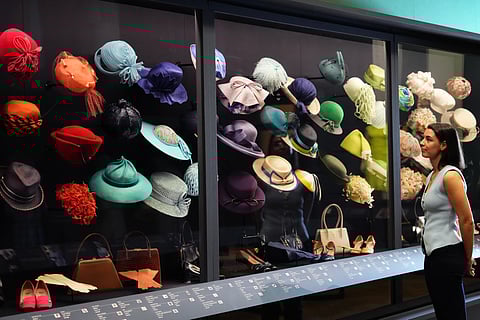 A member of the Royal Collection Trust staff looks towards hats, bags and shoes worn by Princess Elizabeth, on display at 'Queen Elizabeth II: Her Life in Style' exhibition, to mark the centenary of the late queen's birth, 