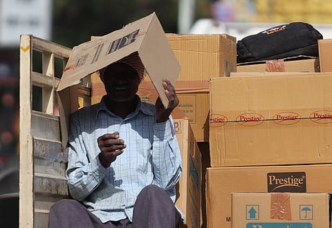 A man uses a piece of cardboard to shield himself from the sun in Secunderabad. 