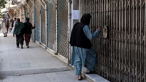 Afghan men walk past shops closed in solidarity with victims killed in an attack by unidentified armed men on the outskirts of the Sayed Mohammad Agha Shia shrine, a day after the incident in Herat on April 11, 2026.