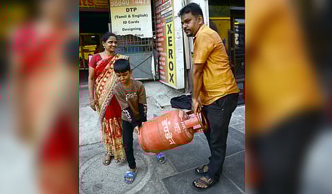 A young boy lends a helping hand to his father to lift LPG cylinder to carry home, amid the ongoing LPG shortage crisis in Chennai.