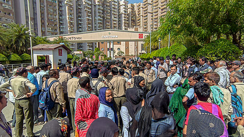 Security guards stage a protest over fee hike issues outside a residential society at Sector 74, in Noida, Tuesday, April 14, 2026.