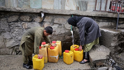 A boy and a girl collect water from a hose connected to a well at a mosque in Deh Mazang, Kabul, Afghanistan, Thursday, April 2, 2026.