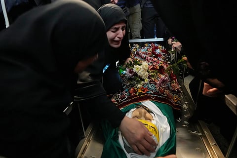 Malak Meslmani, center, the mother of Jawad Younes, 11, who was was killed in an Israeli airstrike, mourns over her son’s body during his funeral procession in Saksakieh village, south Lebanon, Saturday, March 28, 2026.