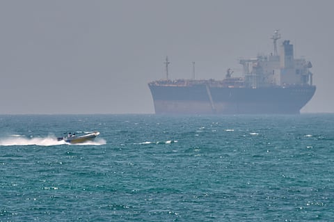 A boat sails past a tanker anchored on the Strait of Hormuz off the coast Qeshm island, Iran, Saturday, April 18, 2026.