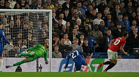 Manchester United's Matheus Cunha (R) starts to celebrate after scoring the opening goal past Chelsea's Spanish goalkeeper Robert Sanchez (L) during the EPL football match between Chelsea and Manchester United at Stamford Bridge in London on April 18, 2026.