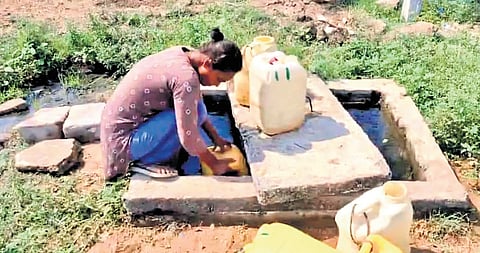 A woman fetches water from an air valve sump of a municipal pipeline at  Ramannapally Colony in Jammikunta of Karimnagar district
