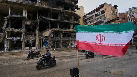 A man on his scooter passes next to an Iranian flag placed in front of a destroyed building, following a ceasefire between Hezbollah and Israel, in Dahiyeh, Beirut's southern suburbs, Lebanon, Monday, April 20, 2026