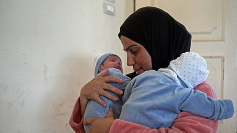 Lebanese displaced woman Ghada Fadel carries her twin sons Mohammed and Mehdi at a shelter for displaced people in the southern Lebanese coastal city of Sidon on April 13, 2026.