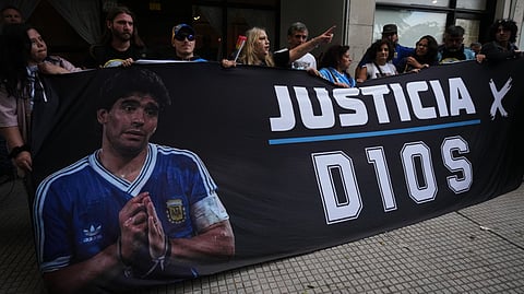 Fans of the late soccer star Diego Maradona stand outside court on the first day of the trial of his medical team for alleged homicide by negligence in San Isidro, Argentina, Tuesday, April 14, 2026. 