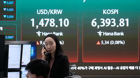 Currency traders talk on the phones near a screen showing the Korea Composite Stock Price Index (KOSPI), right, and the foreign exchange rate between U.S. dollar and South Korean won at the foreign exchange dealing room of the Hana Bank headquarters in Seoul, South Korea, Wednesday, April 22, 2026.
