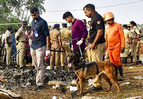 Police personnel with a sniffer dog inspect the site after a blast at a fireworks manufacturing unit at Mundathicode, in Thrissur district.