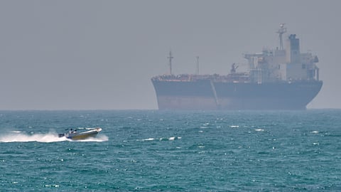 A boat sails past a tanker anchored in the Strait of Hormuz off the coast of Qeshm Island, Iran, Saturday, April 18, 2026.