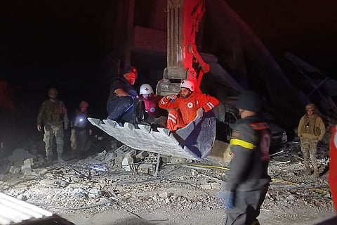 This photo released by the Lebanese Civil Defense, show Lebanese Red Cross volunteers and a Civil Defense worker sit on a excavator carrying the body of the Lebanese journalist Amal Khalil working for the daily Al-Akhbar newspaper killed in an Israeli airstrike, in al-Tiri village, south Lebanon, Wednesday, April 22, 2026. 