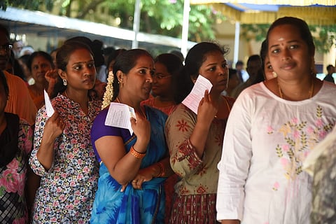 Voters wait to cast their vote at a polling booth during the Tamil Nadu Assembly elections. 