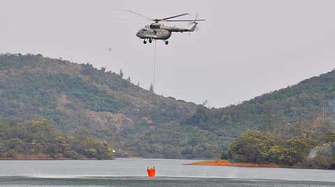 An IAF chopper engaged in filling water at Parshan valley dam to put off forest fire in Nilgirs district on Saturday.
