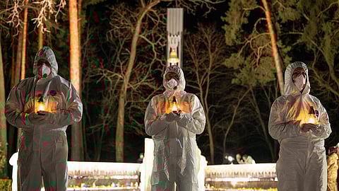 People dressed in white protective suits hold candles during a memorial service dedicated to firefighters and workers who died after the 1986 Chornobyl (Chernobyl) nuclear disaster, ahead of its 40th anniversary in Slavutych, Ukraine, Saturday, April 25, 2026. Chornobyl is the Ukrainian name for the city.