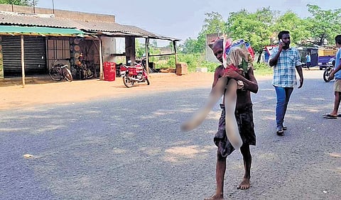 Jeetu Munda carrying his sister’s exhumed body in Mallipashi on Monday.
