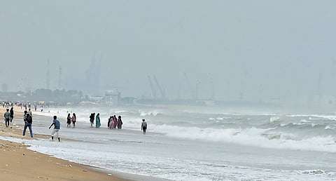 People enter the water at Marina Beach in Chennai as waves lash the shore.