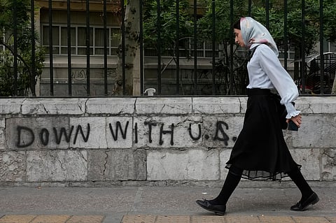 A woman walks past an anti-U.S. graffiti painted on the wall of the Tehran University on Enqelab-e-Eslami (Islamic Revolution) street in downtown Tehran, Iran.
