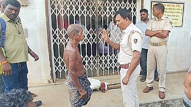 Policemen speak to Jitu Munda in front of the Odisha Gramya Bank branch