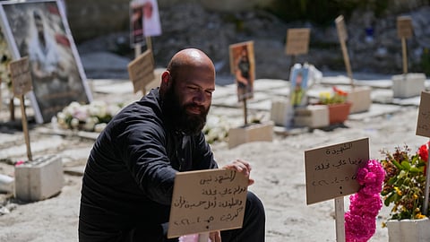 Hussein Farran whose six members of his family were killed in a Israeli airstrike in Kfar Hatta village, visits their graves at a cemetery where civilians and Hezbollah fighters are temporary buried in the southern port city of Sidon, Lebanon, Tuesday, April 14, 2026.