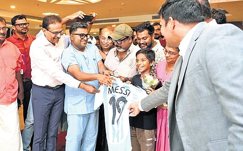 Sports commentator Shaiju Damodaran gifts a jersey to Anosh after nearly two weeks in critical care following a snakebite. The 10-year-old was discharged from hospital on Thursday