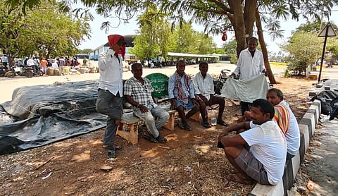 A group of farmers are sitting together and waiting for officials to weigh their maize crop at the Enumamula Agricultural Market in Warangal