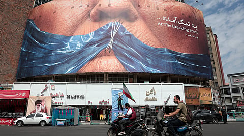 Motorists ride past an anti-US billboard referring to President Donald Trump and the Strait of Hormuz, installed on a building at the Valiasr Square in Tehran on May 2, 2026.