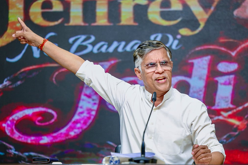 Pawan Khera pointing during press conference with Jeffrey poster